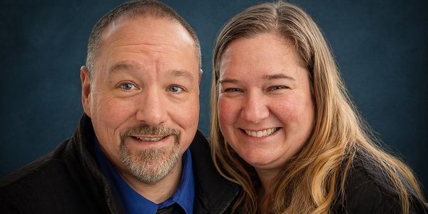 Smiling couple posing against a dark blue background.