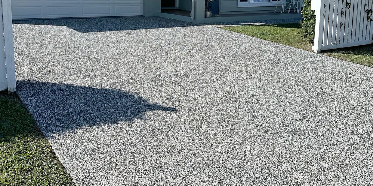 Smooth, speckled driveway leading to a modern garage.