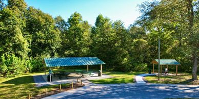 A peaceful picnic area with shelters surrounded by trees.
