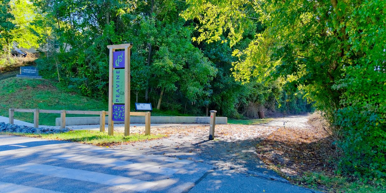 Entrance to Peavine Rail Trail surrounded by green trees.