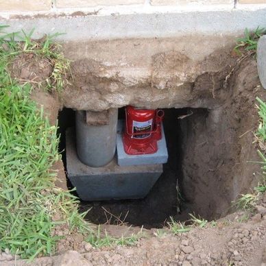 Pressed concrete pier under a slab foundation being lifted with a jack.