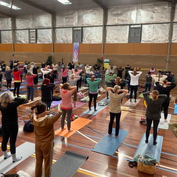Group yoga session in a spacious indoor gymnasium.