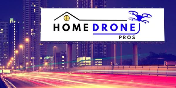 Billboard advertising Home Drone Pros against a city nightscape.