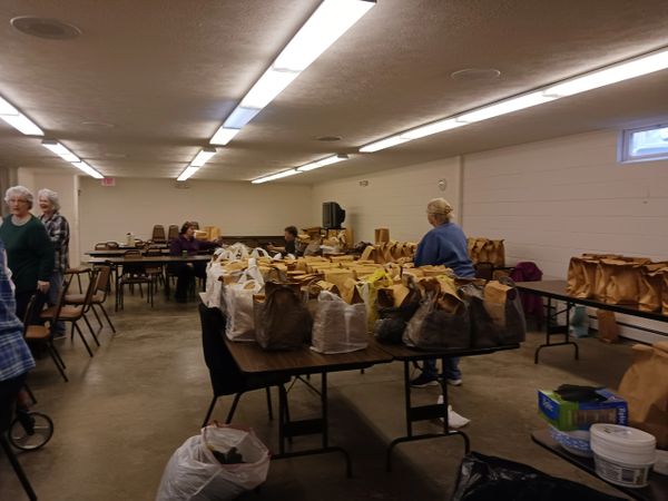 Volunteers organizing and packing bags in a community center room.