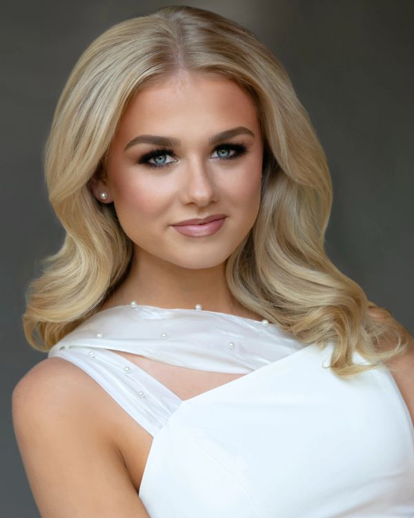 Young woman with blonde hair in a white dress.