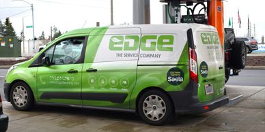 Green and white Edge service company van at a gas station.