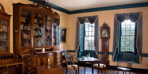 Elegant historic room with antique furniture and large windows.