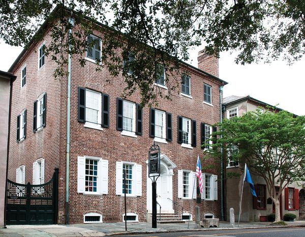Historic brick building with white shutters and American flags outside.