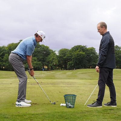 Neil Marr supervising a student in a golf lesson