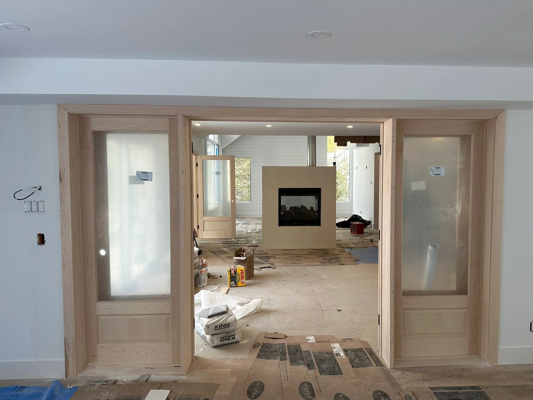 Modern home interior under construction with fireplace and wooden sliding doors.