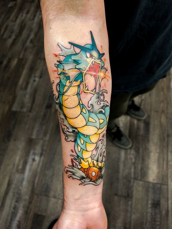 Colorful tattoo of Gyarados and Magikarp on a forearm.