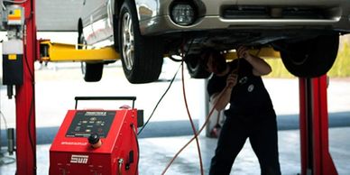 Mechanic doing transmission flush under car.