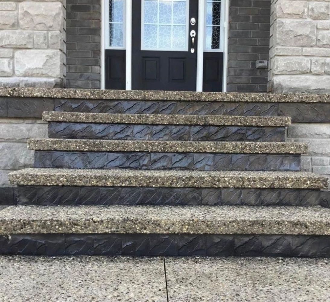 Textured stone steps leading to a black front door with glass panels.