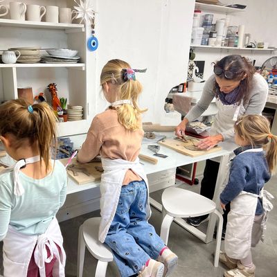 Children and an adult making pottery in a workshop.