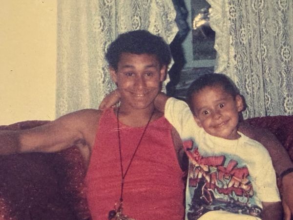 Two boys sitting closely on a couch, smiling.
