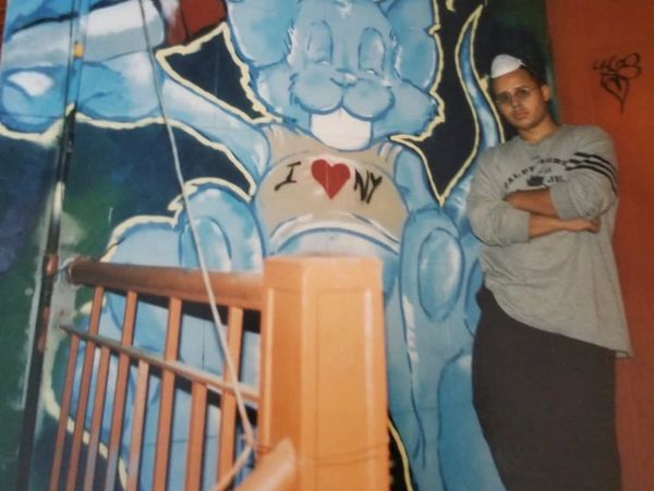 Man posing by a blue graffiti bunny wearing an 'I ❤️ NY' shirt.