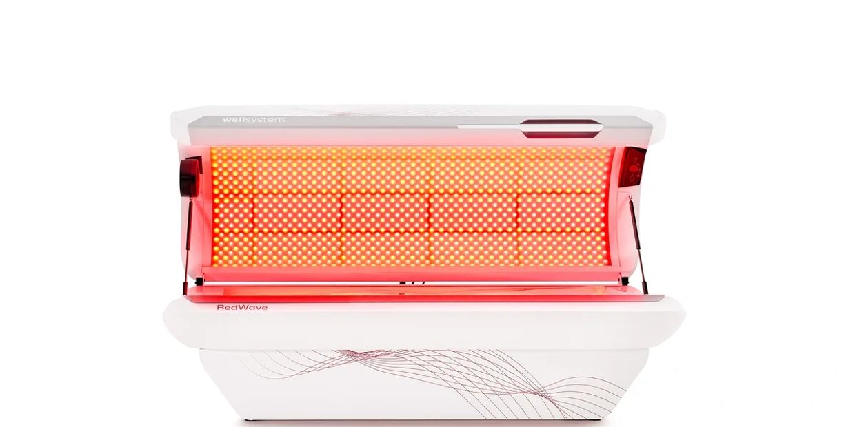 Open red light therapy bed emitting red light.