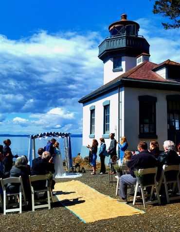 Outdoor wedding ceremony by a lighthouse on a sunny day.