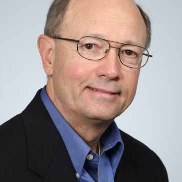 Professional portrait of a middle-aged man wearing glasses and a suit jacket.