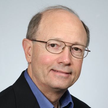 Professional portrait of a middle-aged man wearing glasses and a suit jacket.