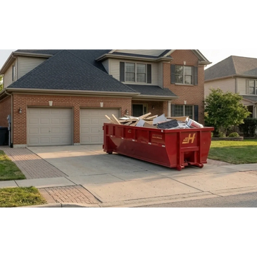 Red dumpster filled with construction debris in front of a suburban house.