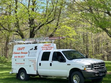 White service truck with Craft Chimney Sweeps branding parked in a green forest area.