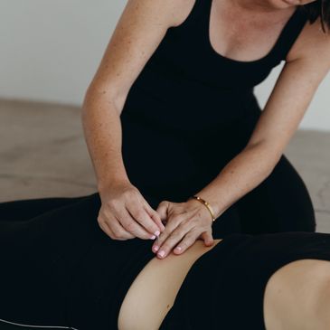 Person performing acupuncture on patient's abdomen.