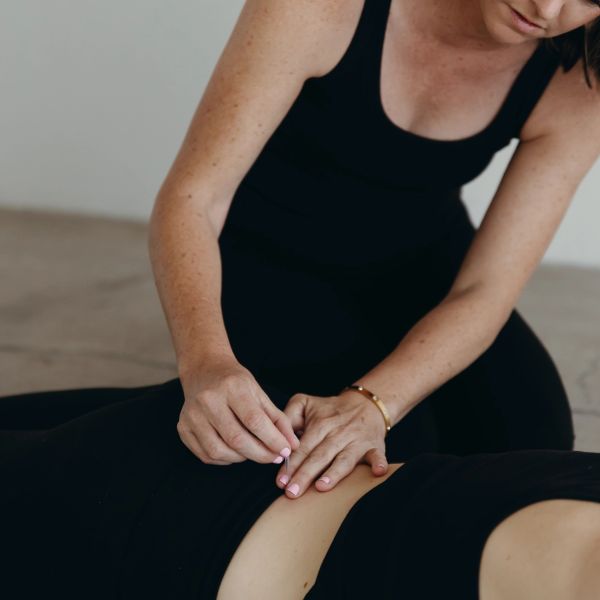A person performing acupuncture on another person's lower back.