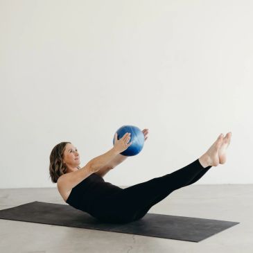 Woman doing Pilates with a blue ball.