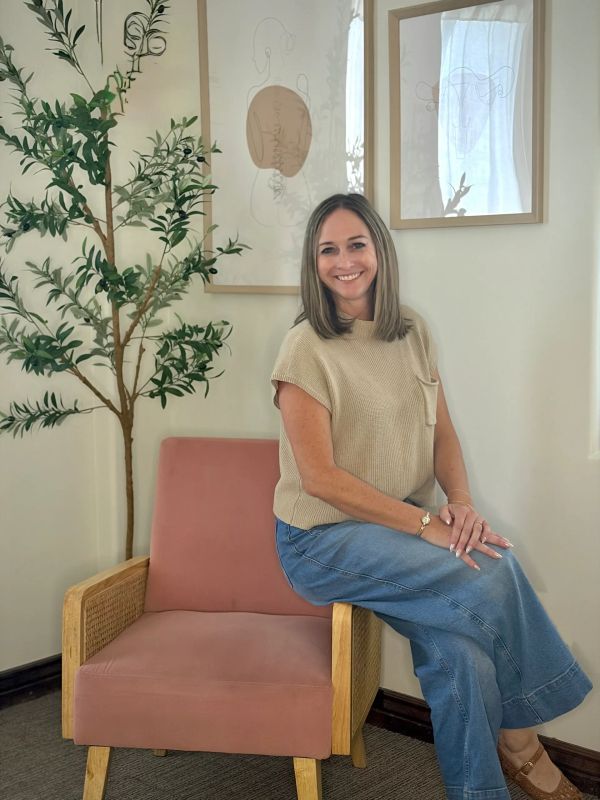 Woman smiling while sitting on a chair in a cozy room.