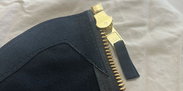 Close-up of a gold zipper on black fabric.