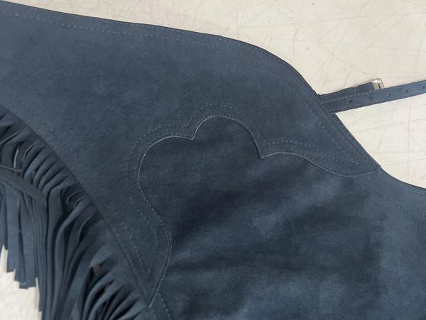 Close-up of dark suede with stitching and fringes.