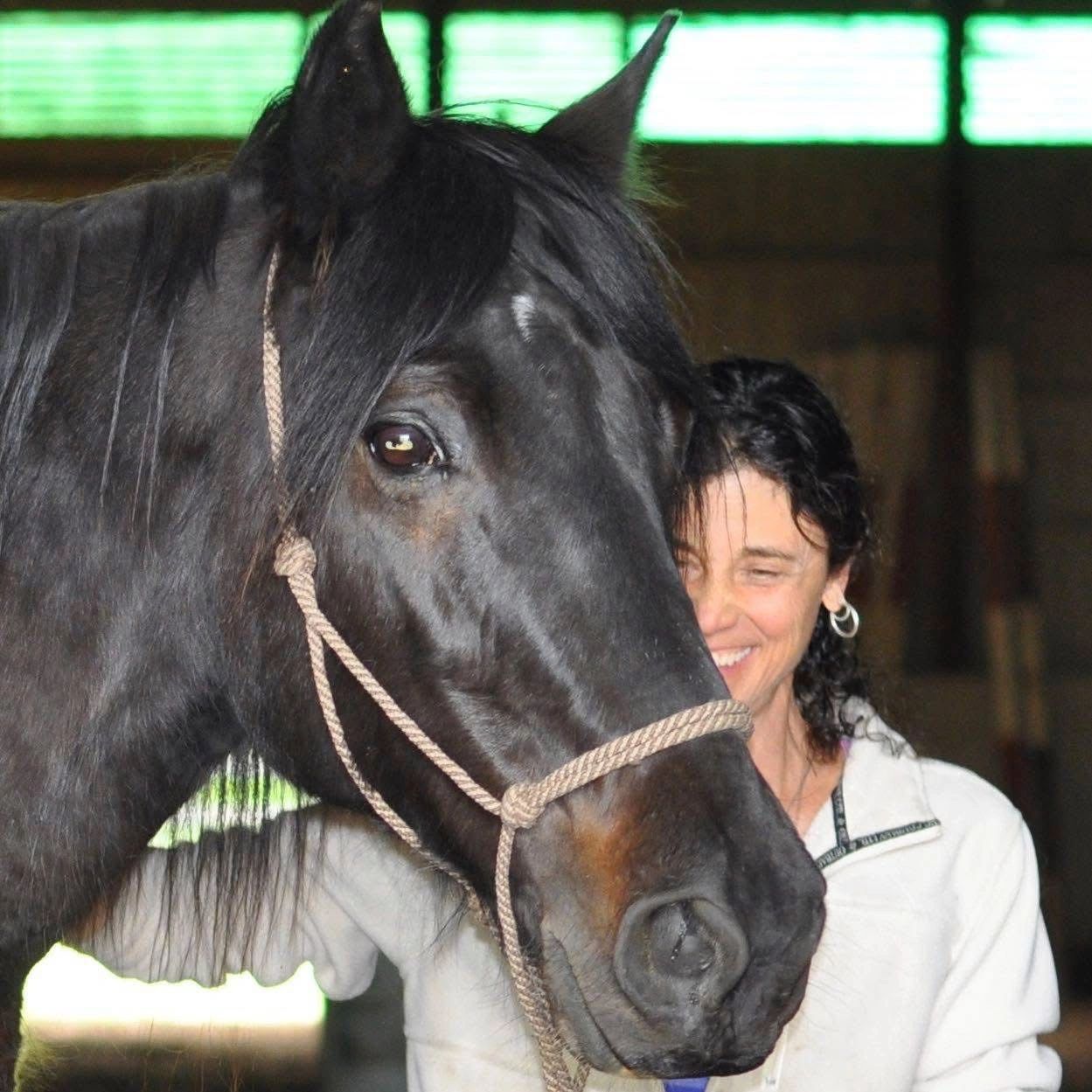Kim leaning close with a black horse.