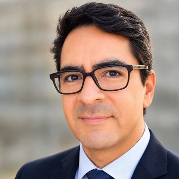 Professional man in glasses and suit smiling slightly.