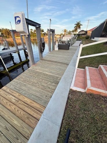 Wooden dock alongside a grassy lawn with steps leading down to it.