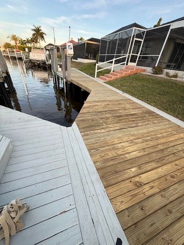 New wooden dock beside a canal with boats and screened patio homes.