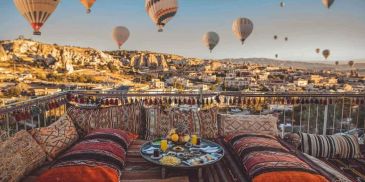 Cozy outdoor seating overlooking hot air balloons at sunrise.