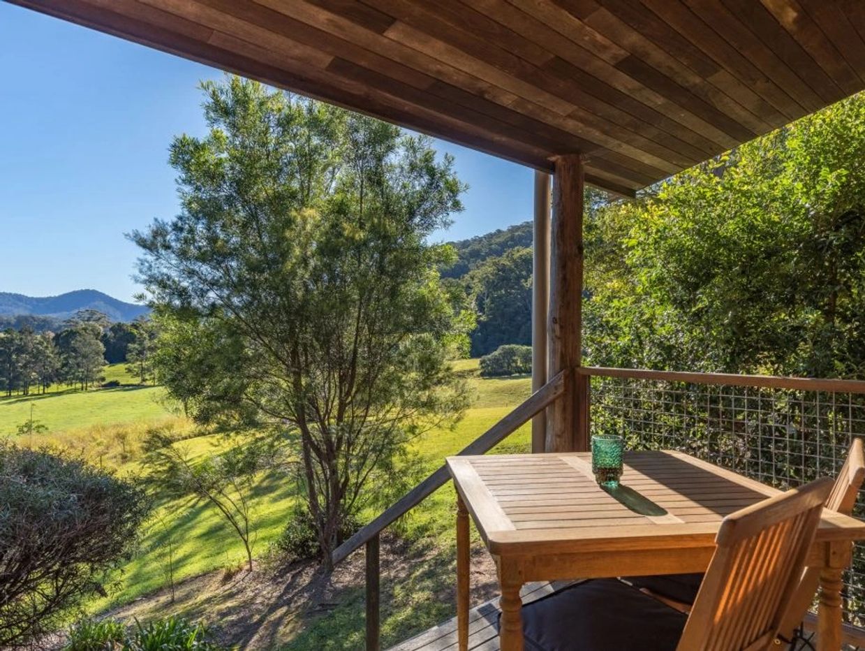 Wooden balcony overlooking lush hinterland green landscape with trees and hills.