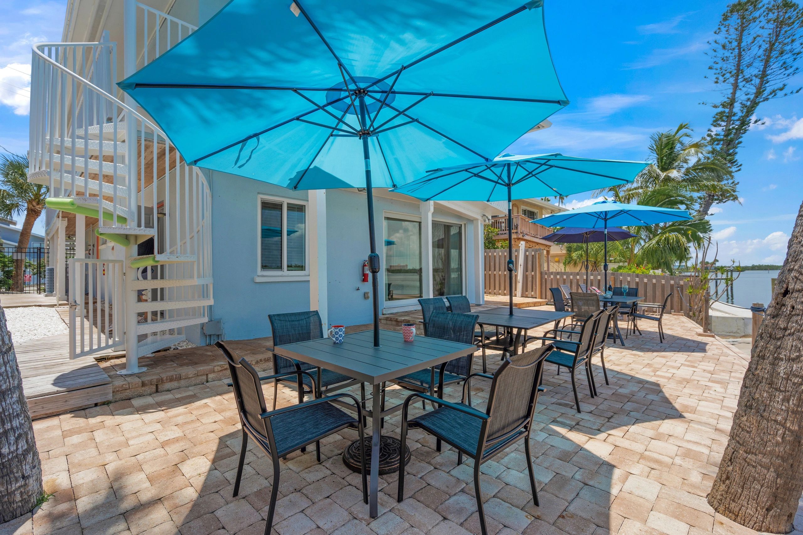 A patio area with tables, chairs, and umbrellas overlooking the water.