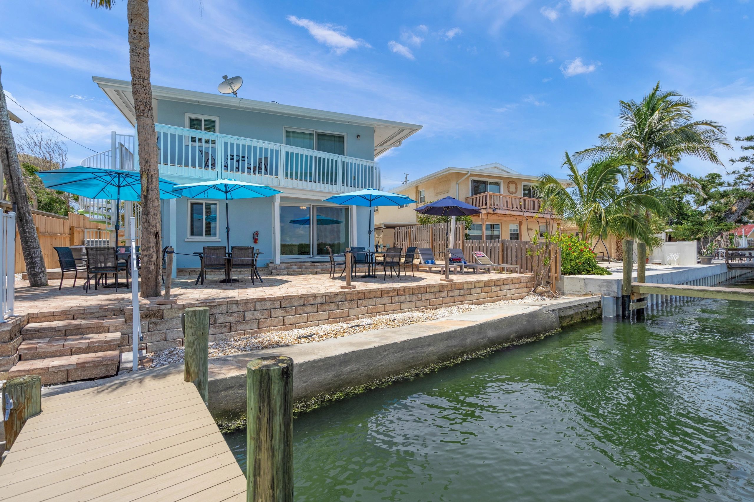 A two-story building with a balcony and patio overlooking a body of water