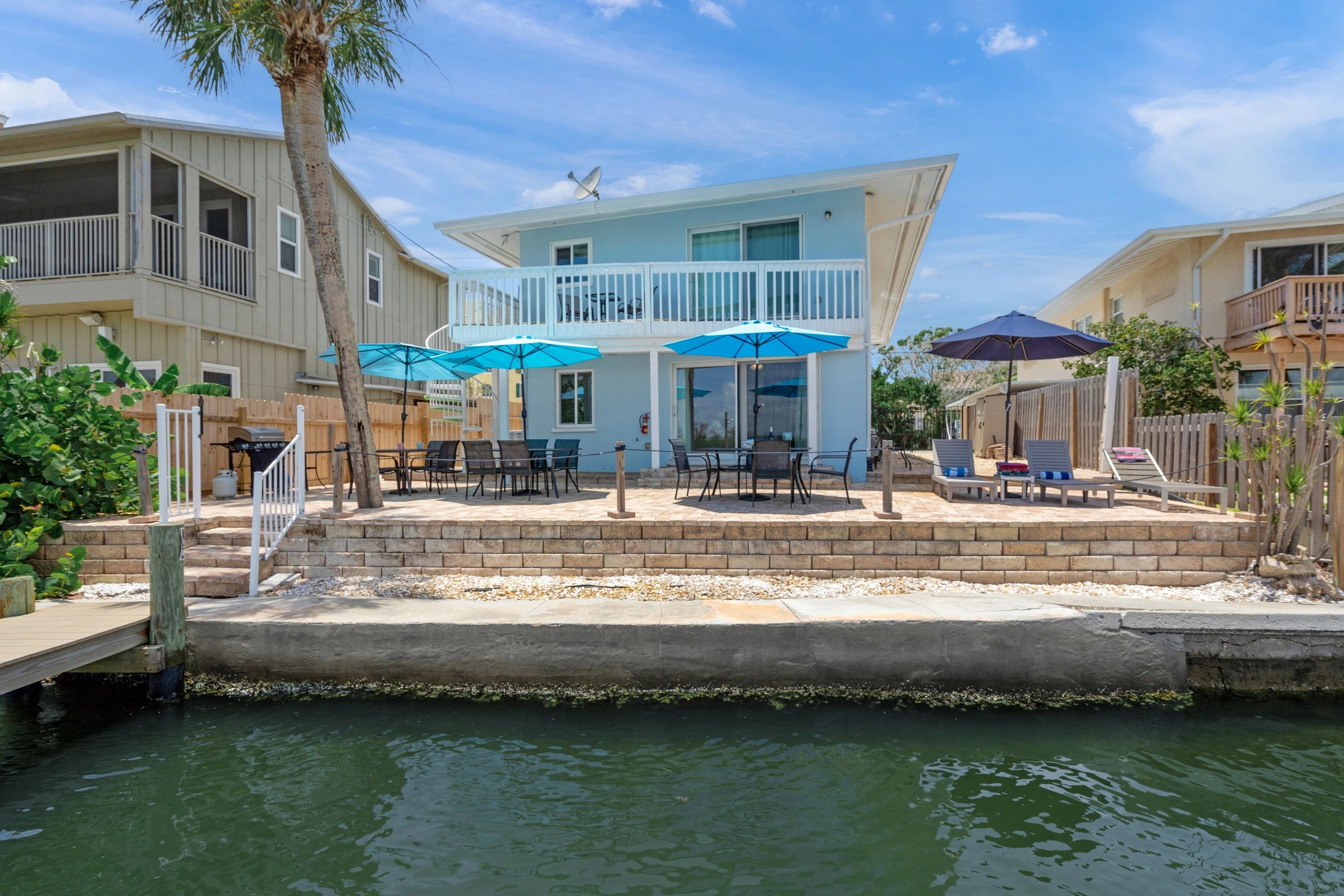 A two-story building with a balcony and patio overlooking the water.