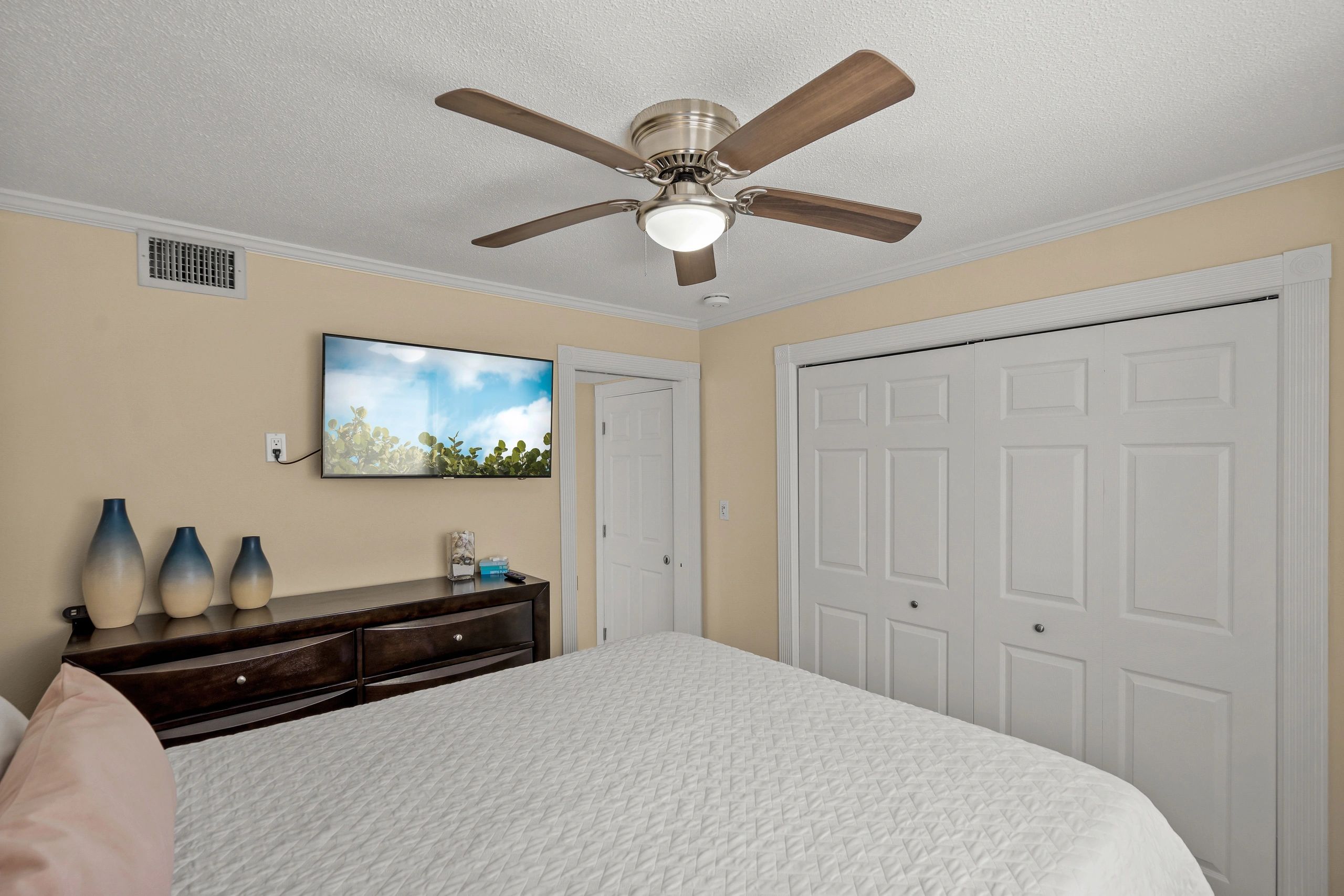 A neatly arranged guest room with a large bed, TV, and closet.