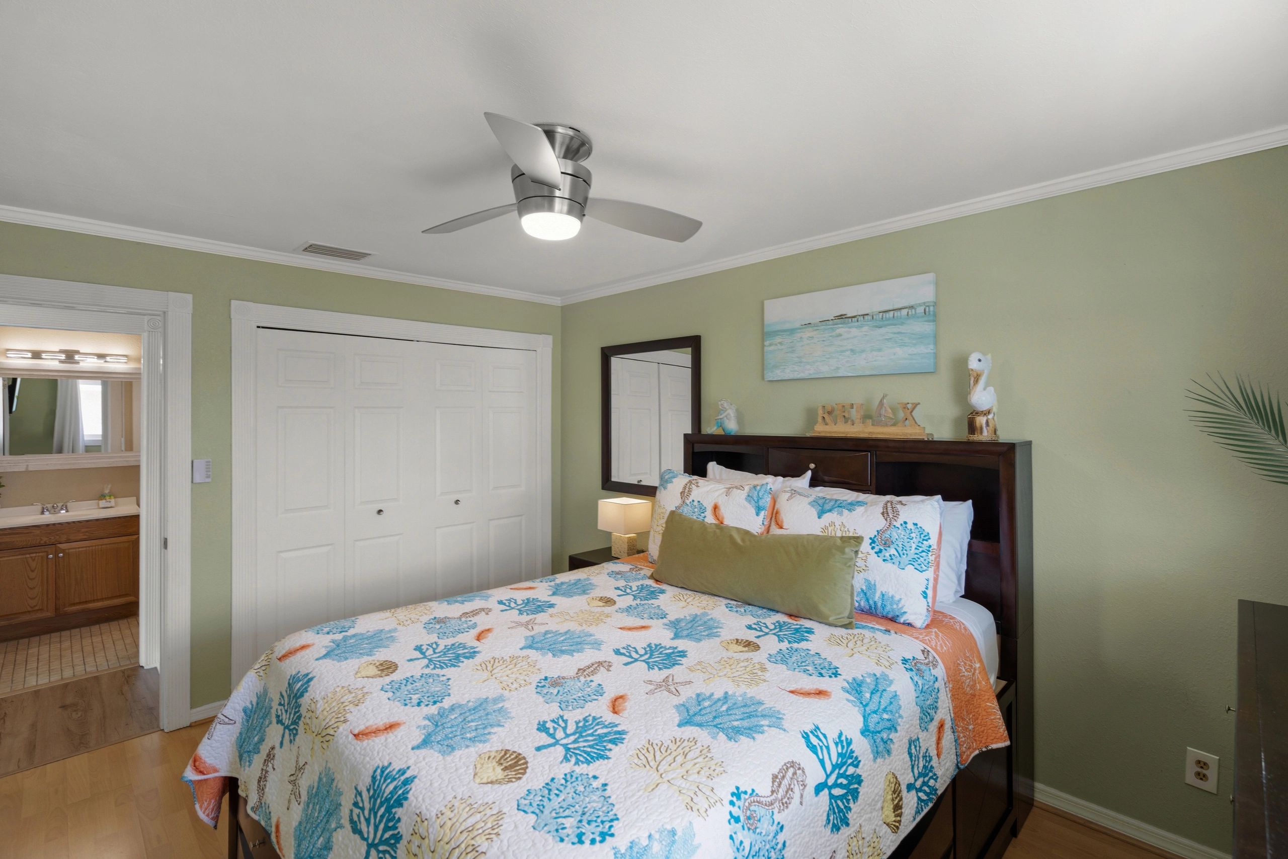 A bedroom with a bed, ceiling fan, and painting on the wall