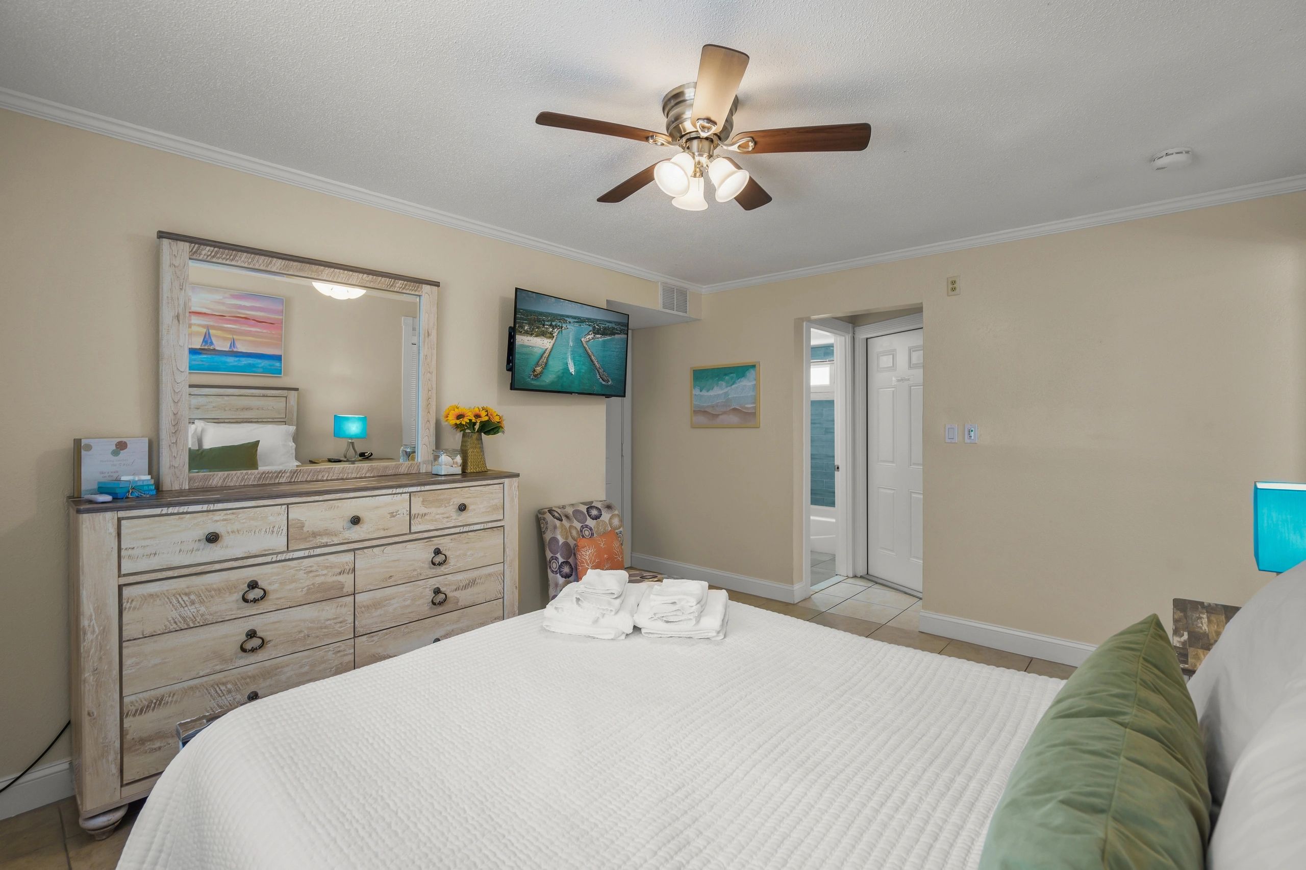 A hotel room with a large bed, dresser, and TV