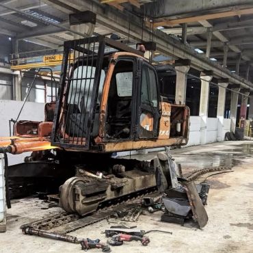 Old construction excavator being repaired indoors.