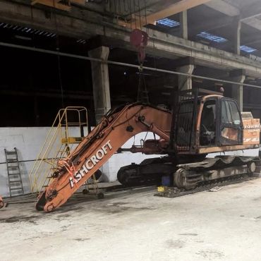 Large orange Ashcroft excavator inside a warehouse.