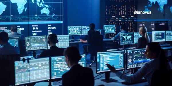 Team of cybersecurity analysts monitoring global data on multiple screens in a high-tech control room.