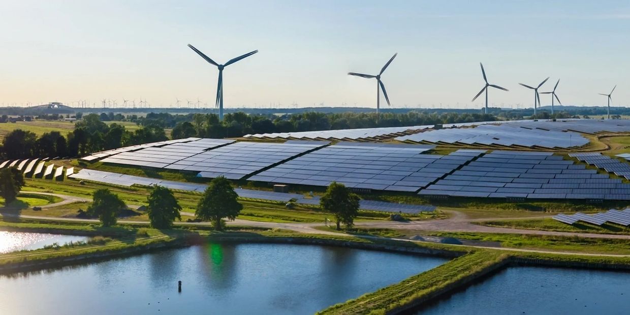 Solar panels and wind turbines near a reservoir illustrating green ammonia energy infrastructure