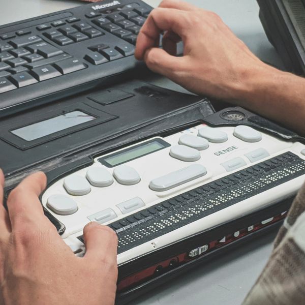 Person reading braille on a digital braille display device.