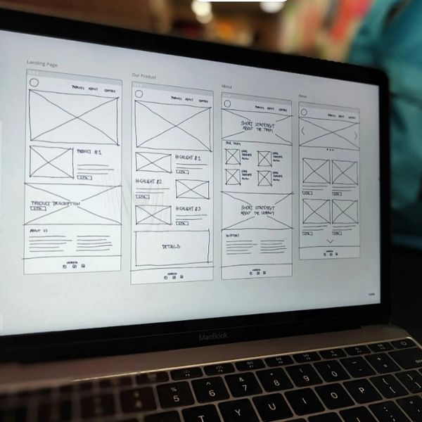 Website wireframe sketches displayed on a MacBook screen.
